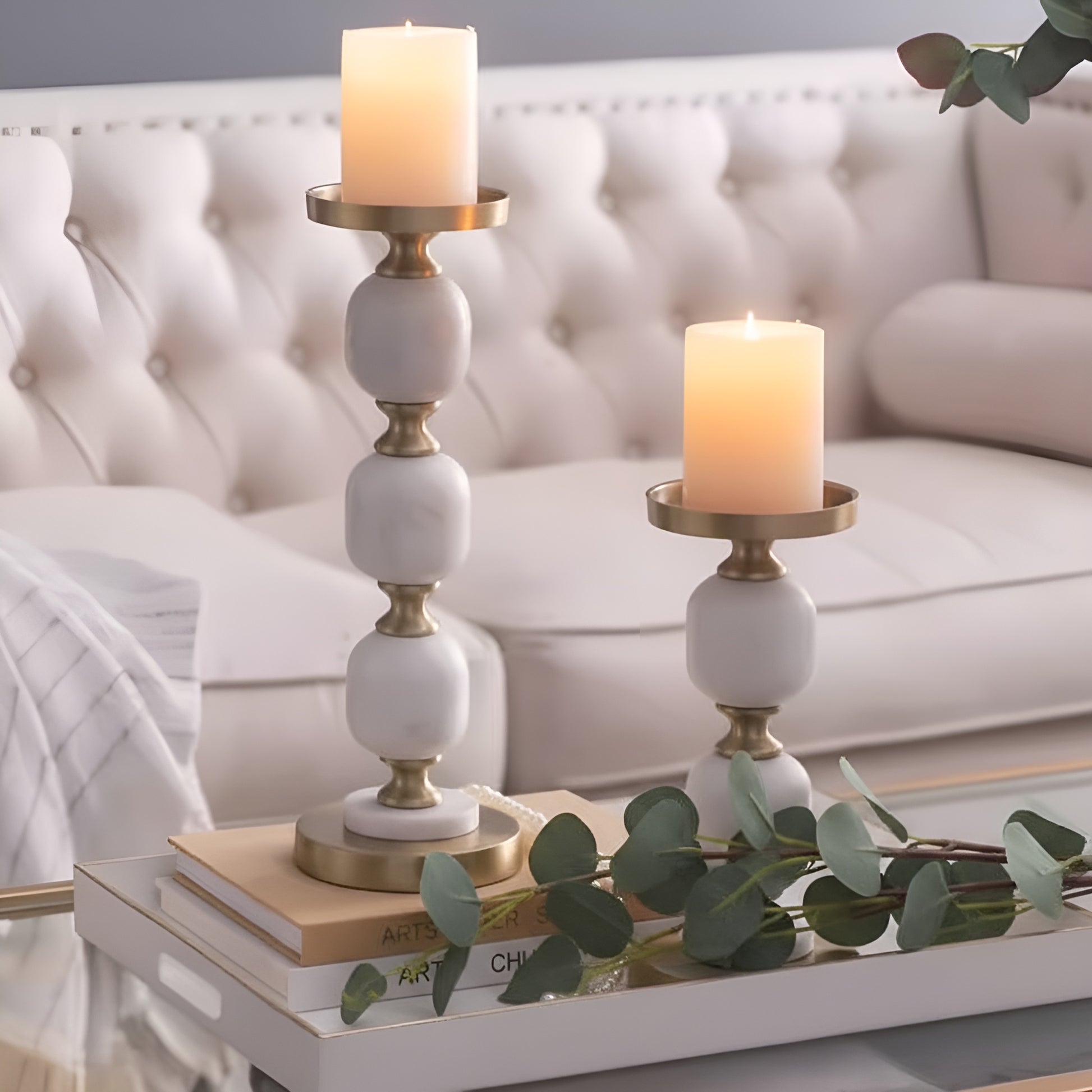 White marble candlestick holders with gold accents styled on a living room coffee table