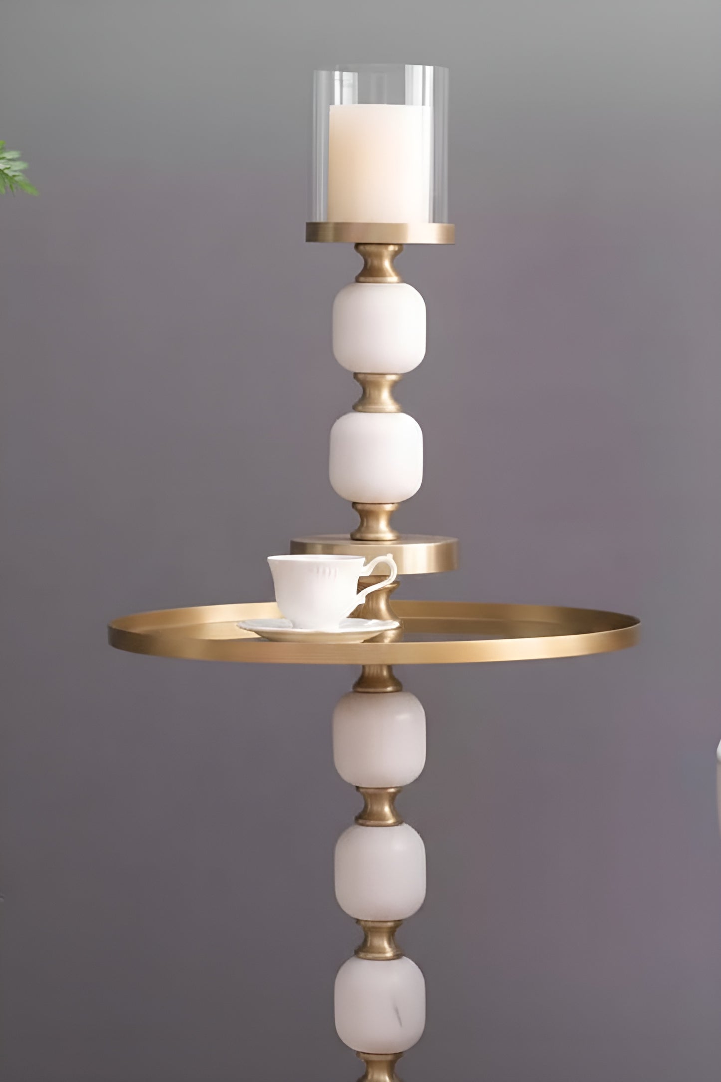 Marble candle holder styled as side table with gold tray and teacup