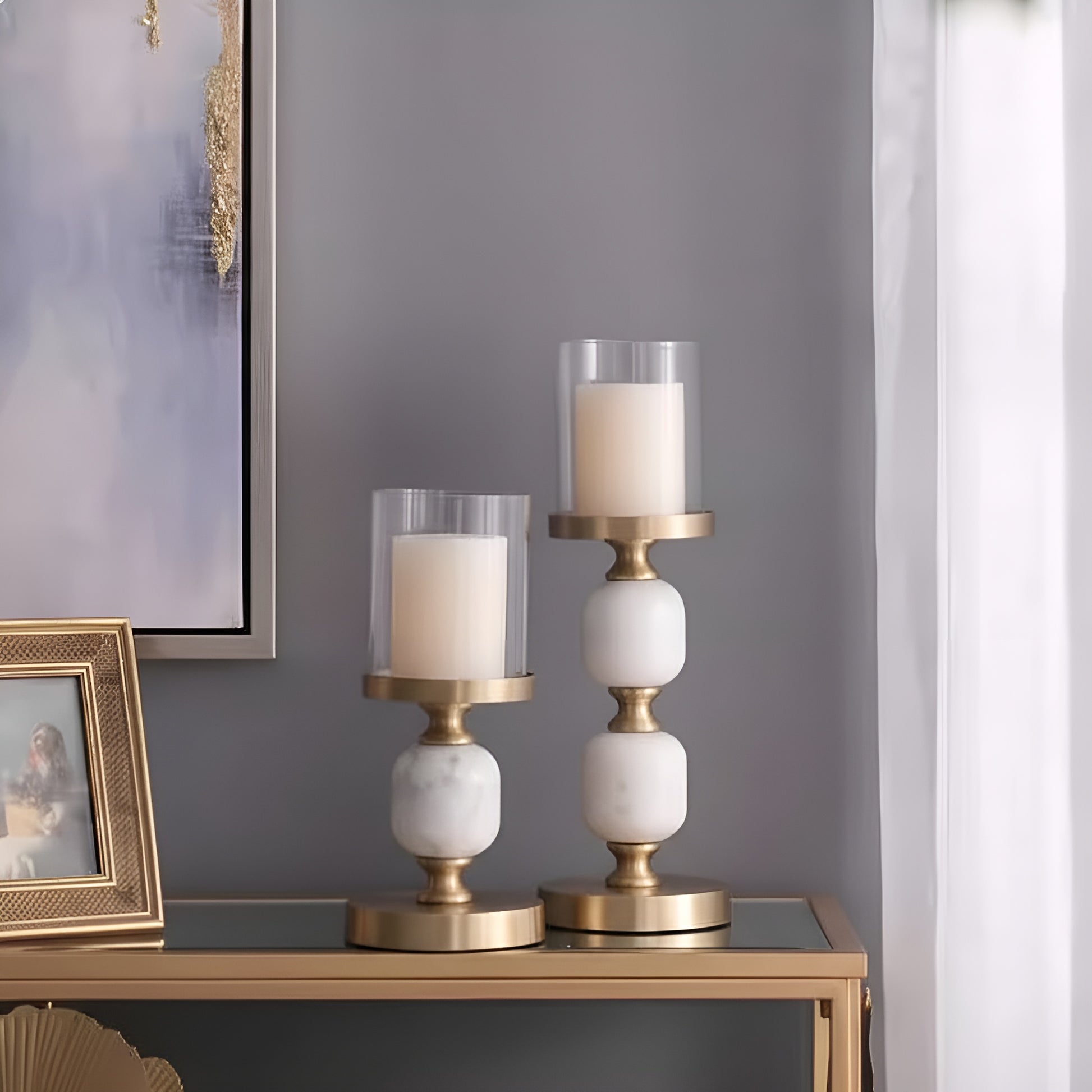 Gold and white marble candlestick holders styled on console table with glass sleeves