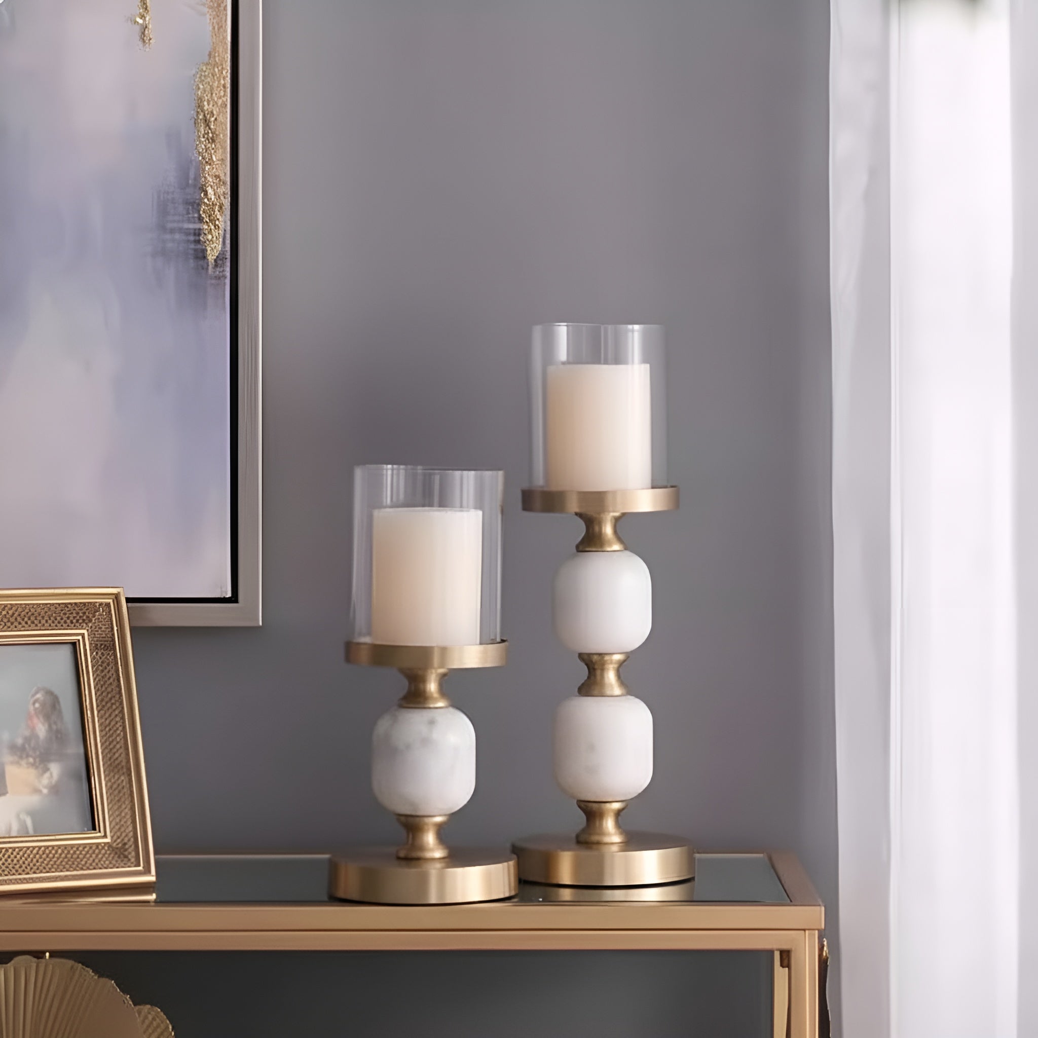 Gold and white marble candlestick holders styled on console table with glass sleeves
